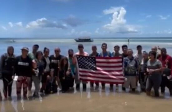 Balseros cubanos sostienen la bandera de Estados Unidos tras llegar a los Cayos de la Florida